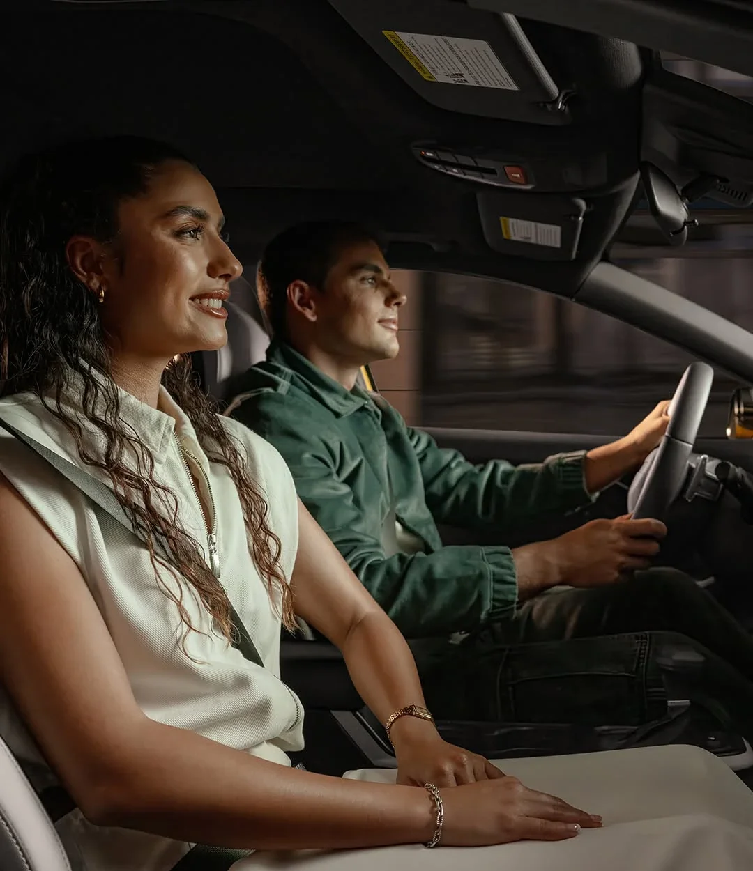 A couple smiling in the front seats of a 2026 Kia K4 Hatchback.