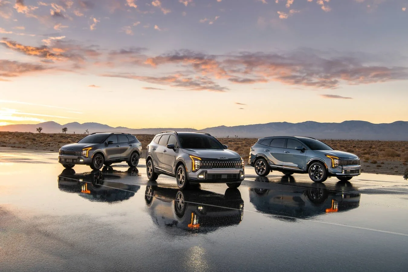 Three Kia SUVs parked on wet ground at sunset, reflected in the water.
