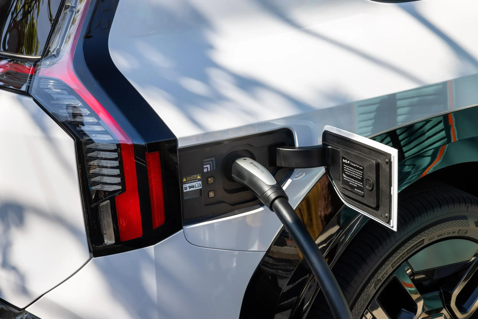 A charging cable plugged into the charge port of a Kia electric vehicle, photographed close up.
