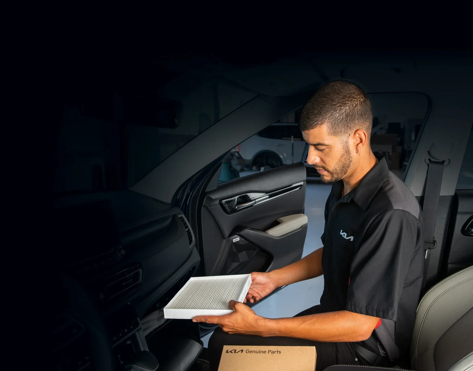 A Kia technician checking a tablet in the driver seat of a car.