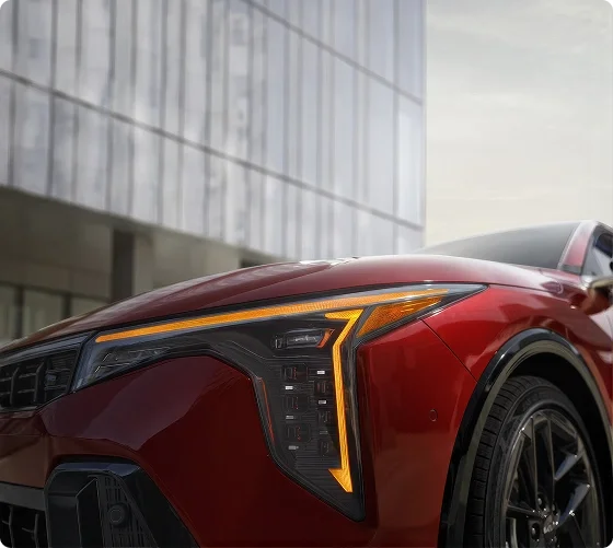 Close-up of the red 2026 Kia K4 GT-Line Turbo front corner showing the vertical LED cube projector headlight and star map daytime running lights