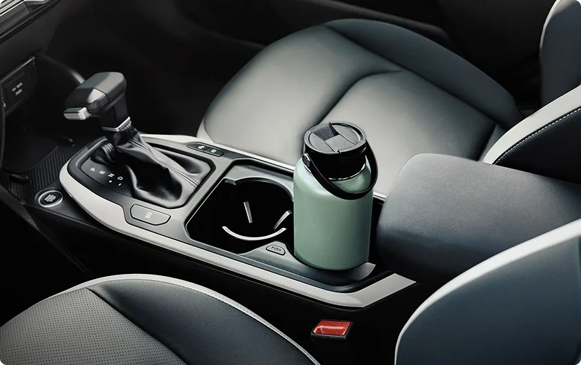 2026 Kia K4 center console with the gear selector and an extra-large travel tumbler in the adjustable cup holder