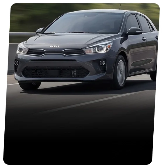 Gray Kia Rio five-door hatchback shown from the front three-quarter view on a dark road