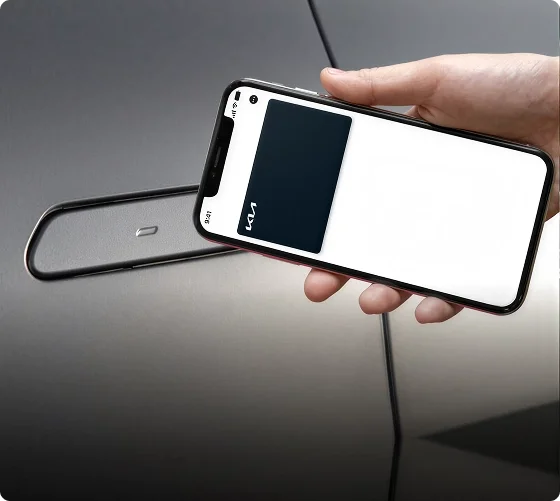 Hand holding a smartphone against the door handle of a Kia to unlock it with Digital Key 2.0