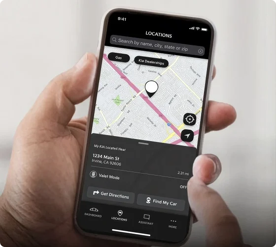 Hand holding a smartphone showing the Kia Access app map with the parked vehicle's location and directions