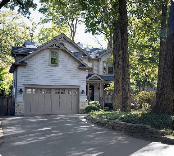 Two-car garage on a suburban home with a driveway framed by tall trees