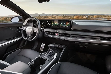2026 Kia K4 driver's view of the steering wheel, digital cluster and touchscreen with a desert road ahead