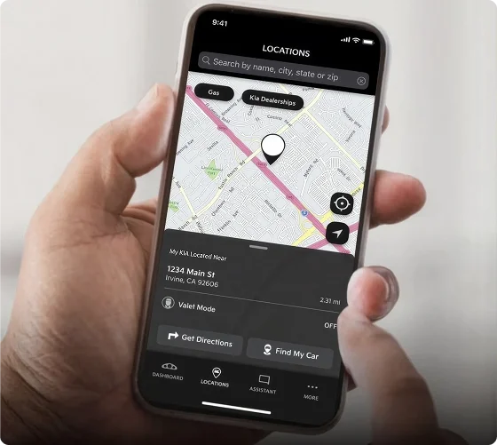 Hand holding a smartphone showing the Kia Access app map with the parked vehicle's location and directions