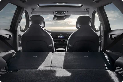 2026 Kia Niro Hybrid cargo area with the rear seats folded flat and a sunset visible through the windshield