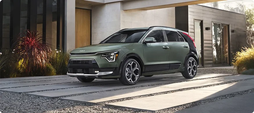 Sage green 2026 Kia Niro Hybrid parked in the driveway of a modern home