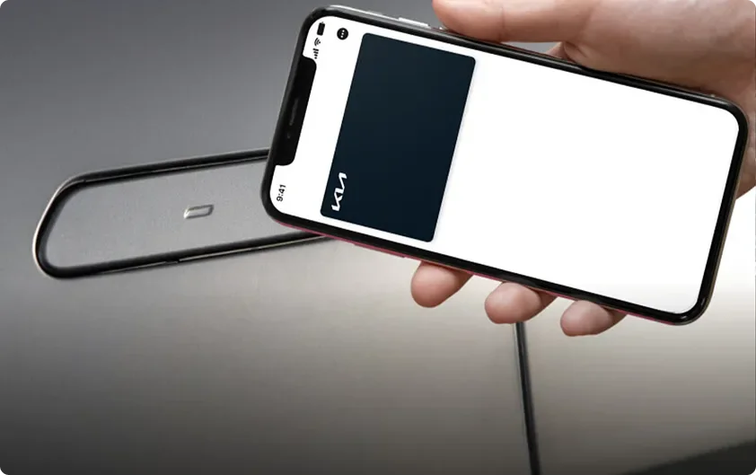 Hand holding a smartphone acting as a Digital Key 2.0 next to a key fob