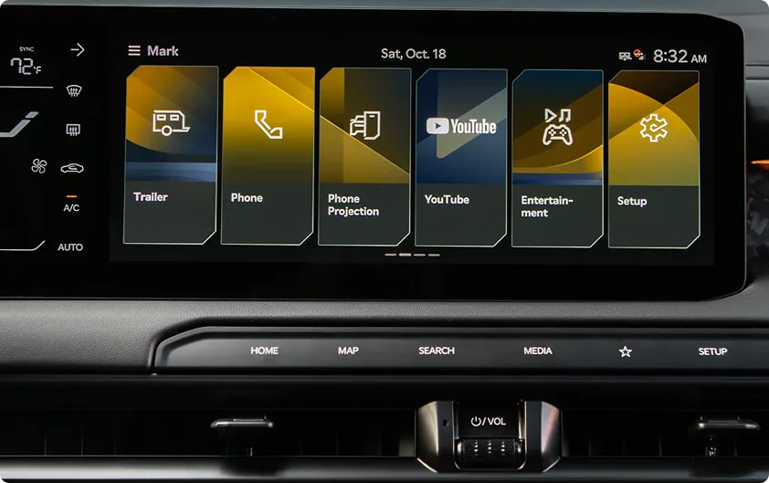 Infotainment touchscreen showing app tiles including Phone Projection, YouTube, and Entertainment