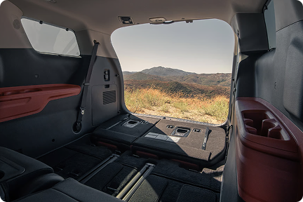 Open sliding door of the Carnival MPV with the rear seats folded flat and a desert view beyond