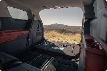 Open sliding door of the Carnival MPV with the rear seats folded flat and a desert view beyond