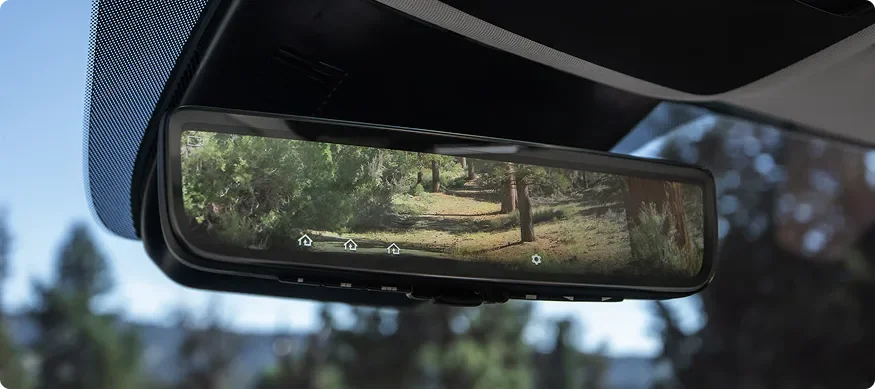 Carnival MPV Hybrid's Full Display Mirror showing a wooded road behind the vehicle