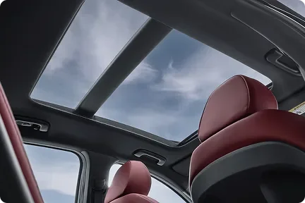 View up through the Kia K5's panoramic sunroof over red leather seats
