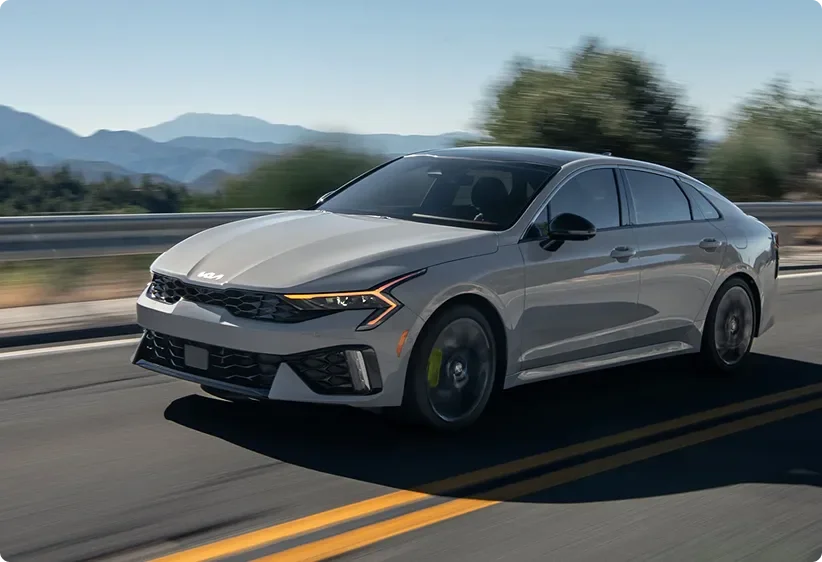 Grey Kia K5 driving on an open highway