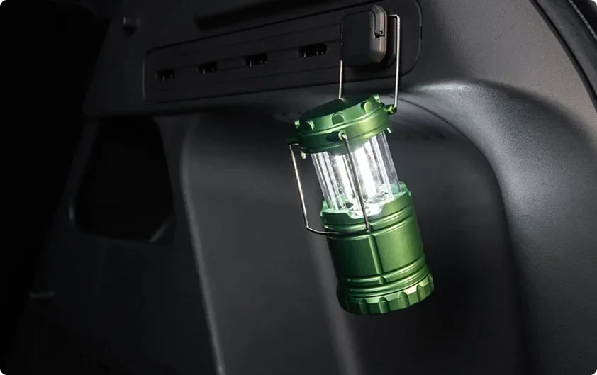 Green camping lantern hanging from a hook in the Seltos cargo area