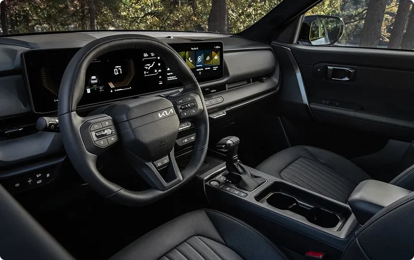 Seltos dashboard and steering wheel with the dual displays lit, seen from the passenger side