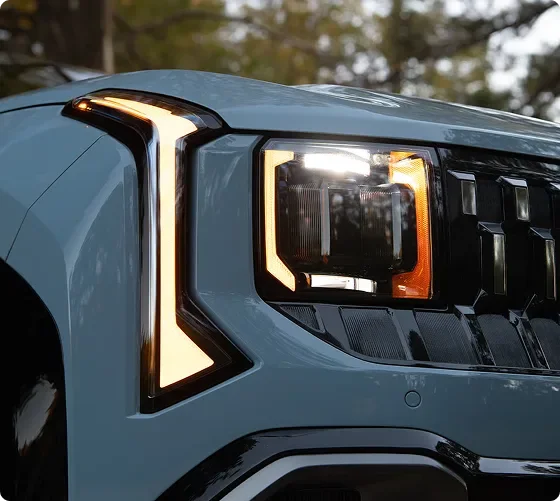 Close-up of a lit Seltos LED headlight on a light blue body