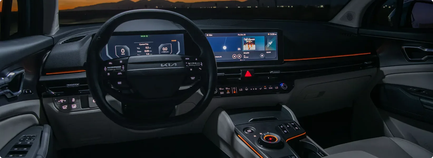 Sportage Hybrid cockpit at night with the curved dual displays and orange ambient lighting lit