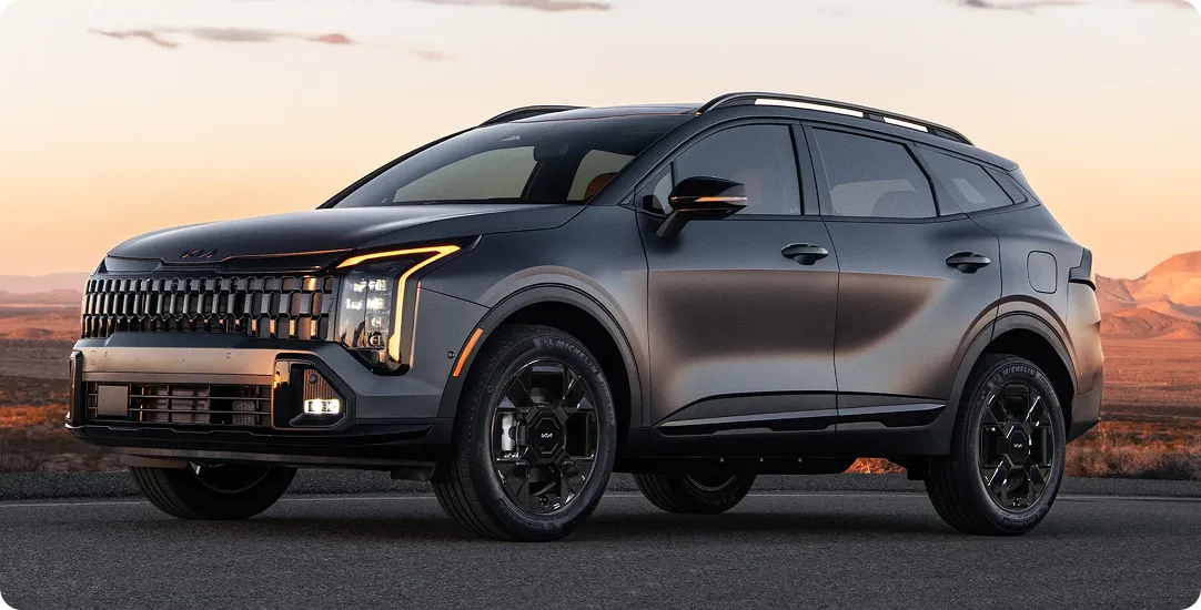Grey 2027 Sportage Plug-in Hybrid parked in the desert at sunset, showing its gloss black wheels and dark accents