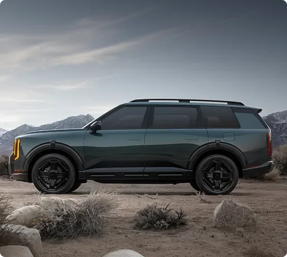 Dark green Telluride Hybrid X-Line in profile on rocky ground below snowy peaks