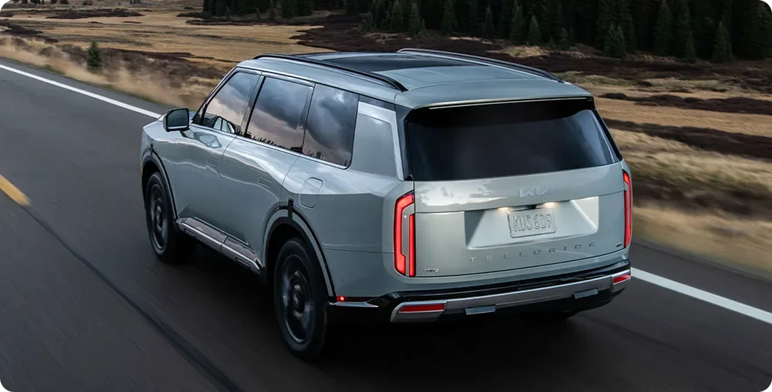 Silver Telluride Hybrid seen from behind on a highway with snow-capped peaks ahead
