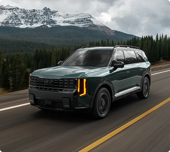 Dark green Telluride Hybrid X-Line driving a mountain highway, front three-quarter view
