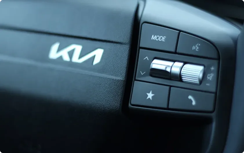 Close-up of the Telluride Hybrid steering wheel voice and mode controls beside the Kia logo