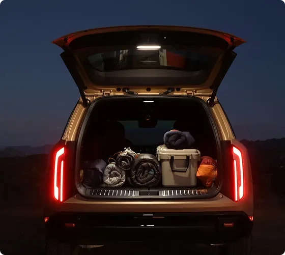 Open Telluride Hybrid liftgate at dusk with the cargo area and gear lit by the liftgate lamp