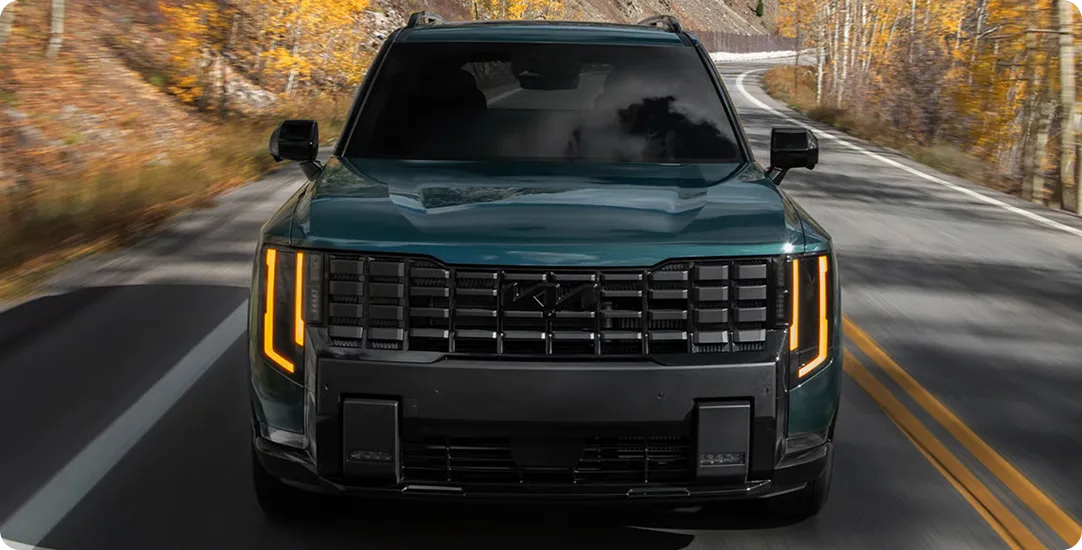 Dark green Telluride Hybrid head-on on a mountain road lined with autumn aspens