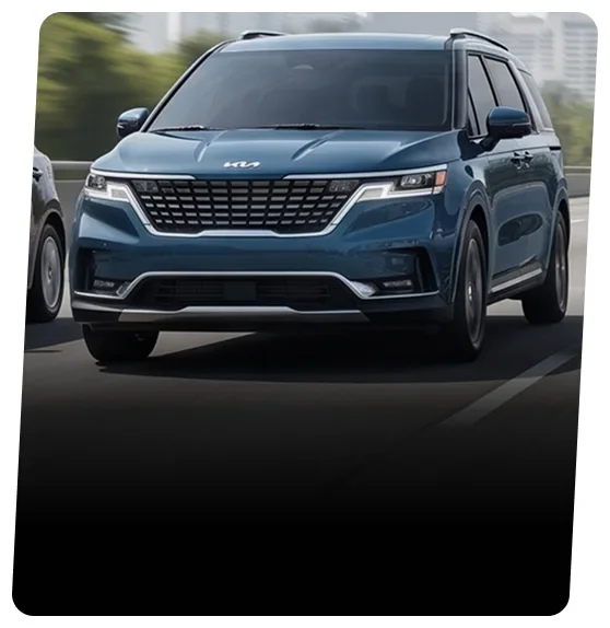 Blue Kia Carnival minivan on a city street