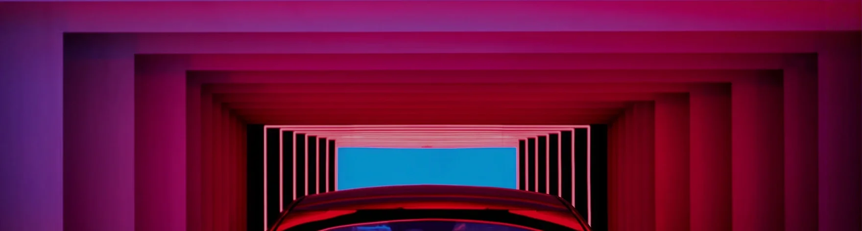 Red Kia viewed head-on through a tunnel of magenta and purple neon light frames