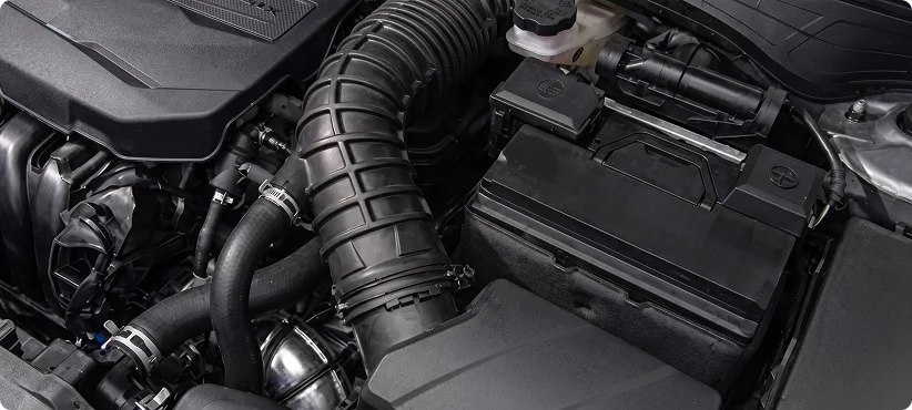 Kia engine bay showing the air intake hose and battery under the hood