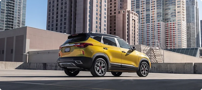 Yellow Kia Seltos parked on a rooftop deck with high-rise buildings behind it