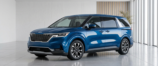 Blue Kia Carnival minivan in a bright studio showroom