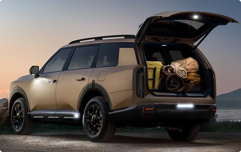 Bronze Telluride at dusk with its liftgate open and ground lighting on, beside camp chairs