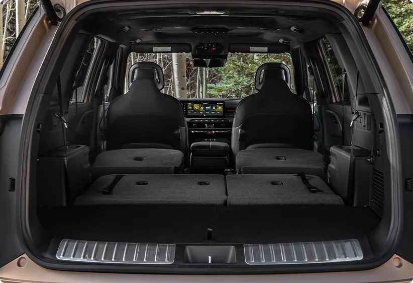 Open Telluride cargo area with the rear seats folded flat and forest behind