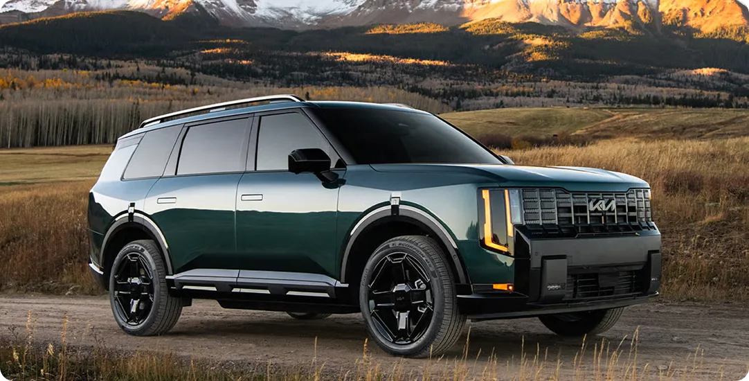 Dark green Telluride X-Line on a dirt road with snow-capped peaks behind