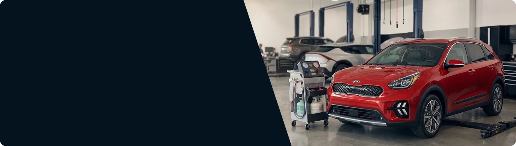 Red Kia Niro beside an AC recovery machine in the Briggs Kia of Topeka service bay