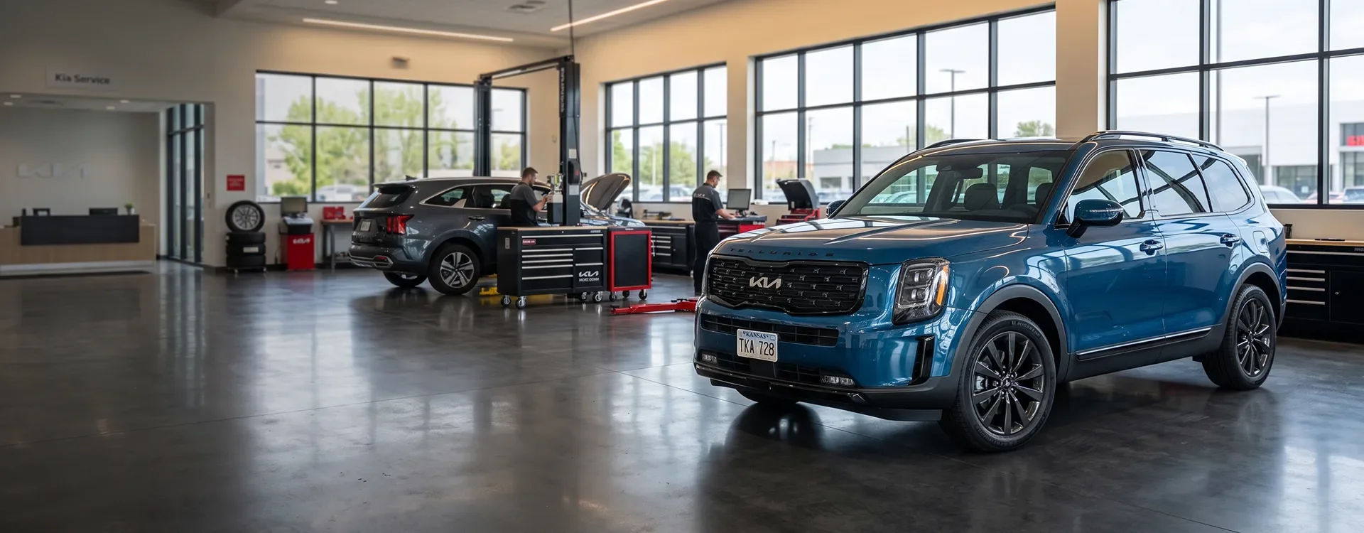 Blue Kia Telluride parked in the Briggs Kia of Topeka service department while technicians work on other Kia vehicles behind it