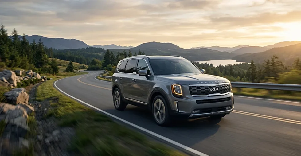 Grey Kia Telluride driving along a mountain highway at sunset