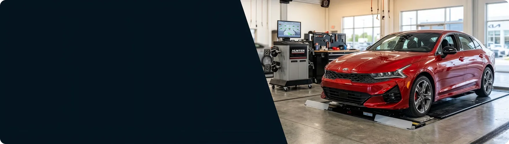 Red Kia K5 on the alignment rack beside the alignment machine at Briggs Kia of Topeka